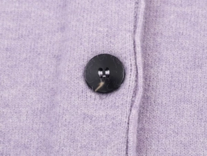 Macro shot of purple knit cardigan detail with a black four-hole button and soft texture