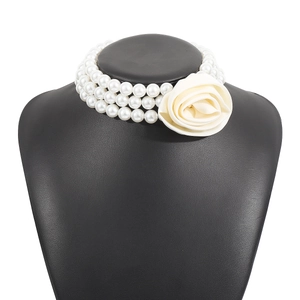 Detailed close-up of a three-layer pearl choker necklace featuring a large fabric rose
