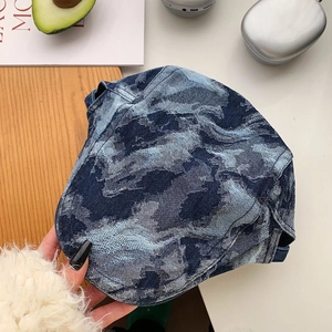 Detail view of denim beret with blue camo pattern and washed texture on wood background