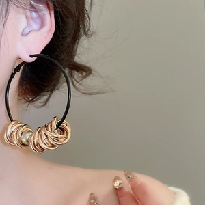 Close-up of black and gold twisted round earrings on model for a unique aesthetic look