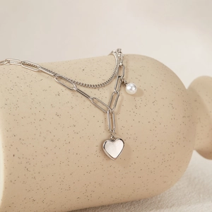 Detail of silver double-layered stainless steel necklace with heart and pearl charms