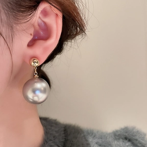 Close-up of elegant grey pearl drop earrings with gold plating on female model