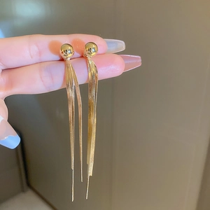 Detail shot of long golden tassel earrings with snake chain and polished beads finish