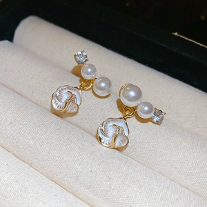Boucles d'oreilles dorées avec perles blanches et fleur émaillée sur velours beige