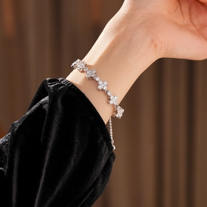 Detailed view of the sparkling zircon clover bracelet on a wrist with silver finish