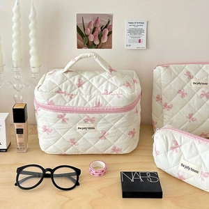 Quilted makeup bag set with pink bow print on wooden table with elegant accessories