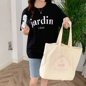Close-up of large canvas tote bag with PARIS print and casual black embroidered T-shirt