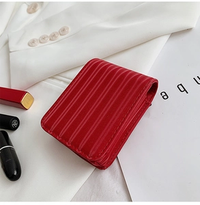 Close-up of red vertical quilted leather lipstick case with compact mirror and accessories