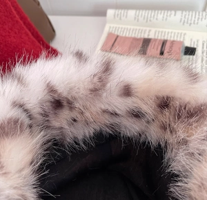 Close-up of black fuzzy bucket hat with spotted faux fur trim and soft plush texture