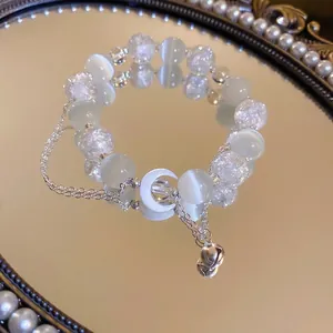 Cat eye stone moon bracelet with silver bell on a vintage mirror surface