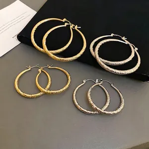 Textured hoop earrings set in gold and silver with hammered finish and ribbed design