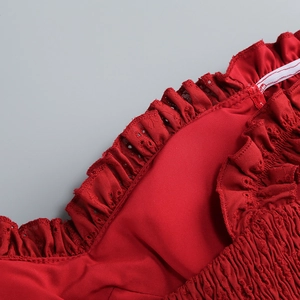 Detail of red off-shoulder dress featuring intricate lace embroidery and ruffled hemline