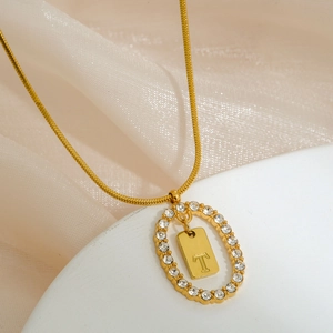 Macro shot of gold oval letter T pendant with micro-set rhinestones on snake chain