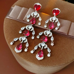 Macro view of silver earrings featuring ruby heart and waterdrop zircon fringe tassels