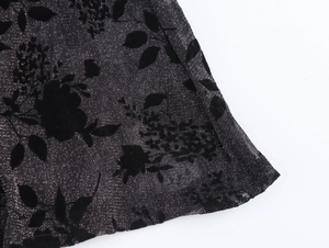 Macro shot of black translucent mesh fabric with flocked floral patterns and metallic threads