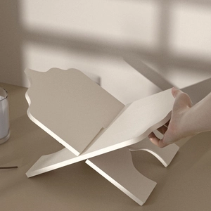 Minimalist cream-colored X-shaped reading bookstand with elegant wavy curved design