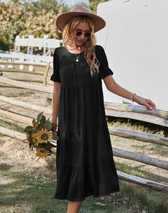 Détail d'une robe mi-longue noire à étages avec manches courtes et ourlet à volants