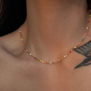 Close-up of 18k gold plated necklace with vibrant colorful enamel beads on collarbone