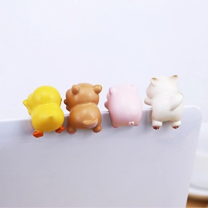 Mini resin animal ornaments of a duck, bear, pig, and cat hanging on a laptop screen edge