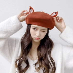 Detail of caramel wool beret with cute animal ears worn with a white plush cardigan