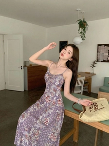 Détail d'une robe mi-longue fleurie violette à fines bretelles en tissu léger au café