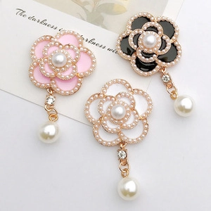 Detailed view of pearl and rhinestone camellia flower brooches in white, pink, and black