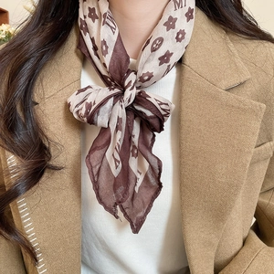 Detailed texture of brown printed silk scarf paired with a camel blazer in soft light