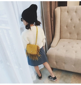 Detail view of yellow tassel crossbody bag styled with autumn children's outfit
