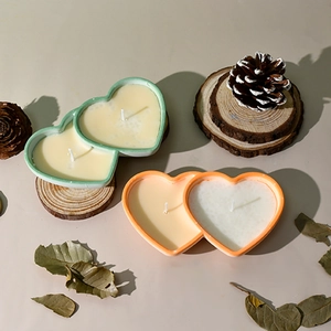Detail of heart-shaped ceramic candle holders with two wicks in mint green and orange