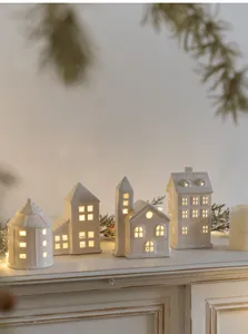 Ceramic house night lights set on a fireplace mantel with festive Christmas pine decoration