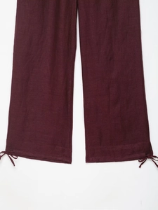 Detailed close-up of dark burgundy linen lantern pants with adjustable drawstring cuffs