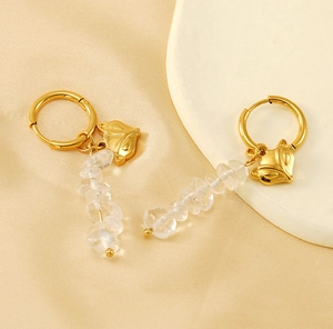 Close-up of golden fox earrings with irregular moonstone beads on silk background