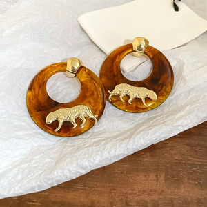 Detailed close-up of amber resin hoop earrings with gold cheetah and silver needle backing