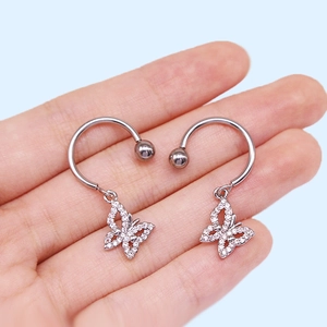 Macro shot of silver-tone C-shape nipple rings with sparkling butterfly pendant details