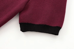Close-up of burgundy knit sweater sleeve with black ribbed cuffs and fine stitching