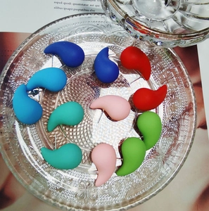 Macro detail of teardrop resin earrings in multiple colors on a vintage glass tray