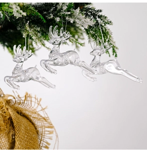 Detailed view of clear acrylic reindeer ornaments hanging on snow-covered pine branches