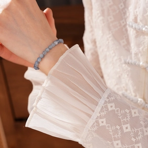 Close-up of blue crystal beaded bracelet on wrist with elegant lace cuff detail