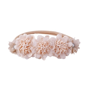 Detailed view of baby flower headband with light apricot fabric petals and pearl center