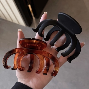 Detail of large black matte and amber glossy plastic shark hair clips for thick hair