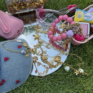 Marine charm jewelry set with gold starfish and shells on a mirror over grass background