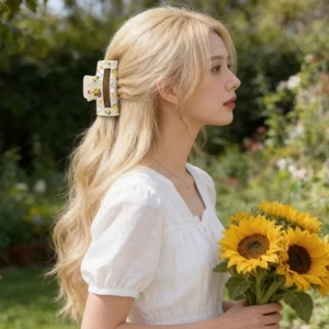 Dettaglio del fermaglio rettangolare con api e fiori tra i capelli biondi