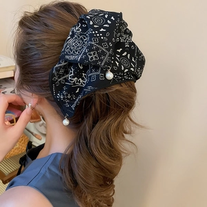 Detail of paisley print fabric hair claw with white pearl pendants on a ponytail