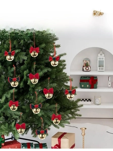 Detailed view of red velvet bows with golden bells hanging on a Christmas tree branch