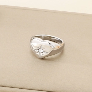 Macro shot of silver heart signet ring with starburst cz stone on leather background