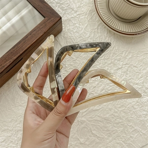 Three triangular acetate hair claws in marble patterns including brown, black, and white