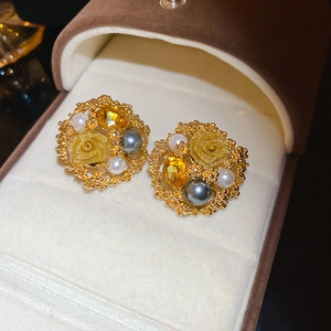 Macro detail of vintage gold flower earrings with grey pearls and yellow gemstones
