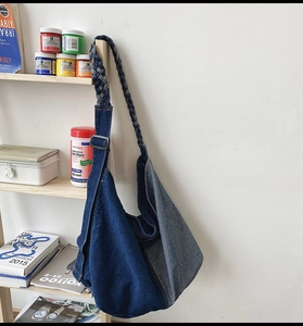 Detail of blue patchwork denim crossbody bag with wide woven shoulder strap and large capacity