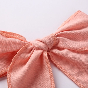 Macro detail of the pink linen fabric texture and stitching on a child's bow hair clip