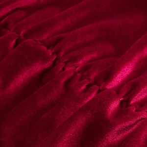 Vue macro du tissu en velours bordeaux avec texture plissée détaillée sur la robe